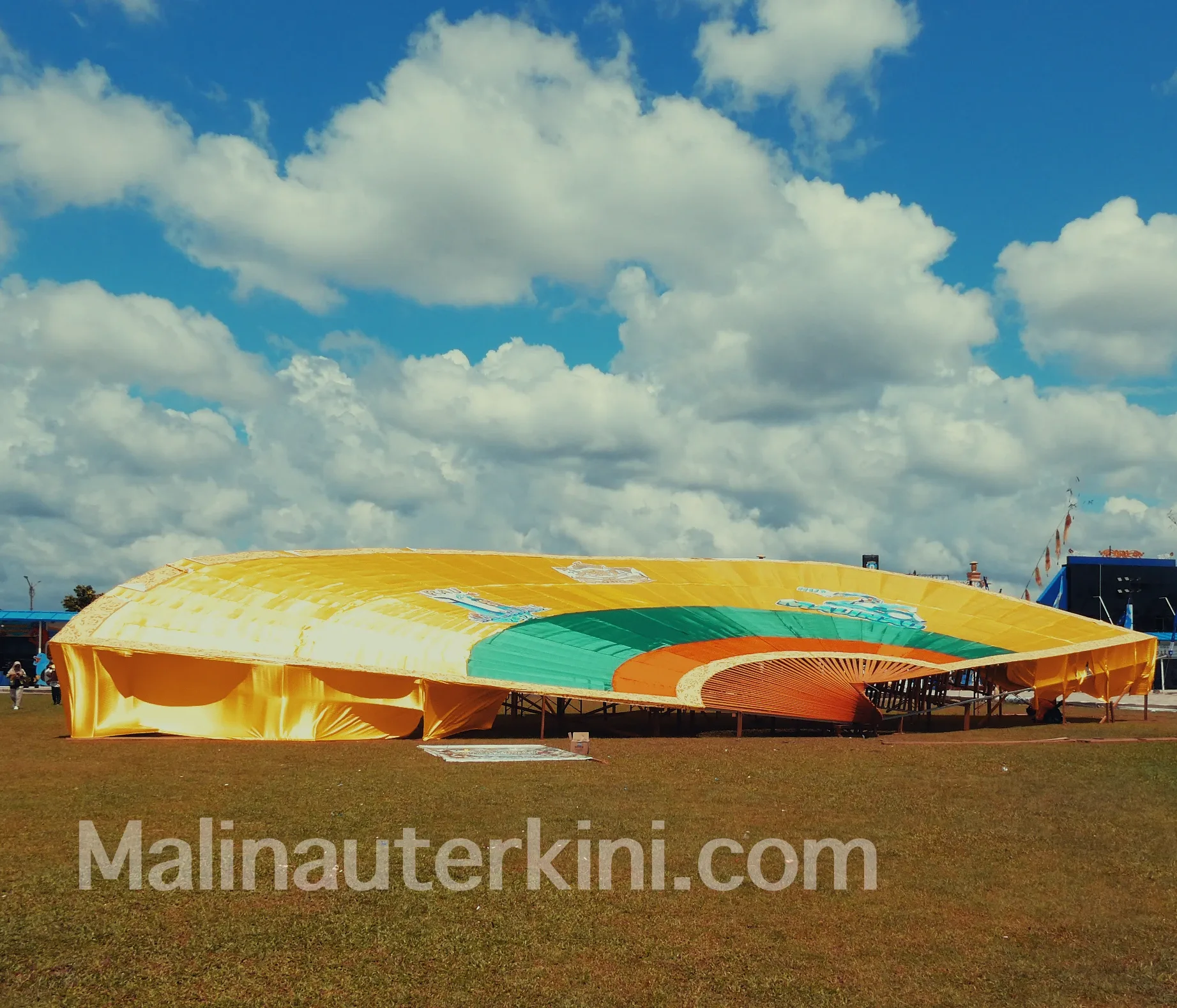 DEDAP SEBENUA – Kipas emas raksasa 30 meter membentang megah di area panggung utama. Instalasi budaya ini menjadi ikon penampilan Lembaga Adat Bulungan pada Irau Malinau 2025.