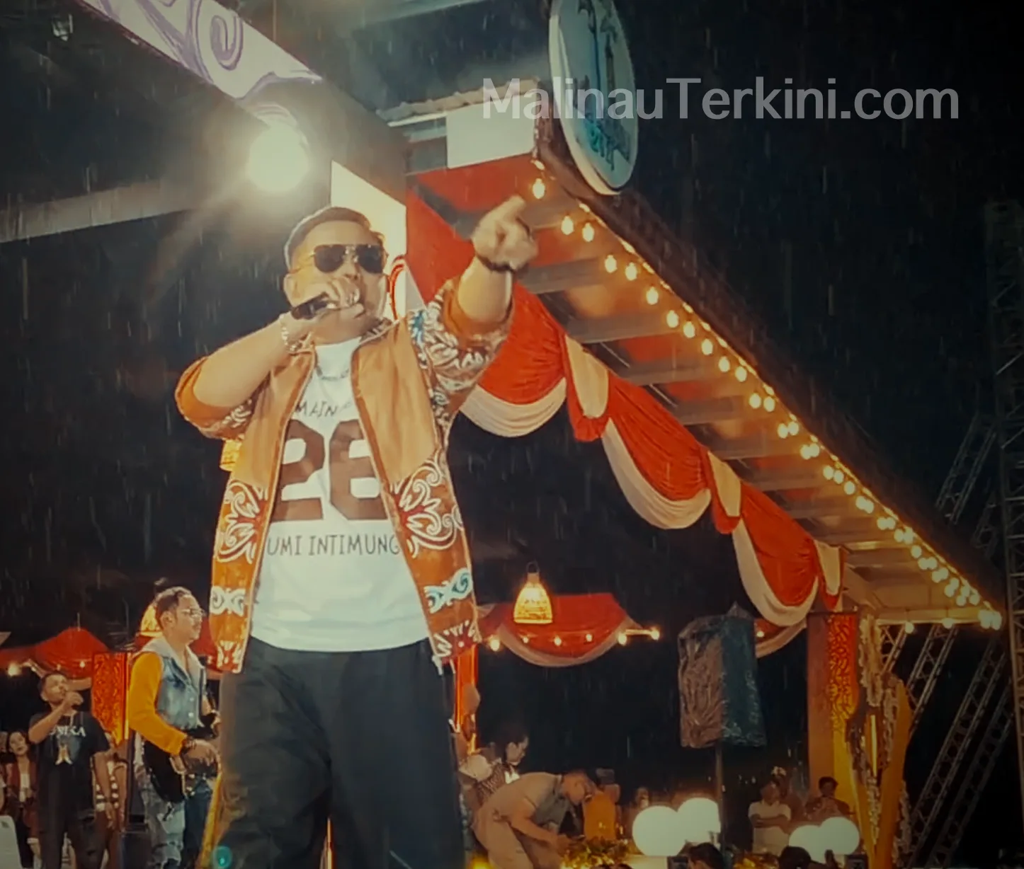 Judika tampil di panggung Irau Malinau 2025 dengan sweater motif etnik saat hujan deras dan penonton tetap antusias.