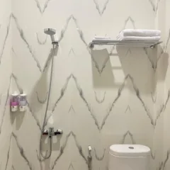 Kamar mandi Hotel Dotaga Malinau dengan shower modern, water heater, toilet bersih, dan perlengkapan mandi lengkap.
