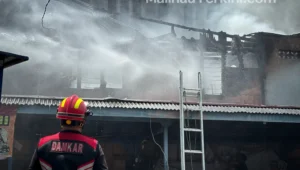 Petugas damkar memanjat atap kios untuk menjangkau sumber api di Pasar Kuliner Malinau.