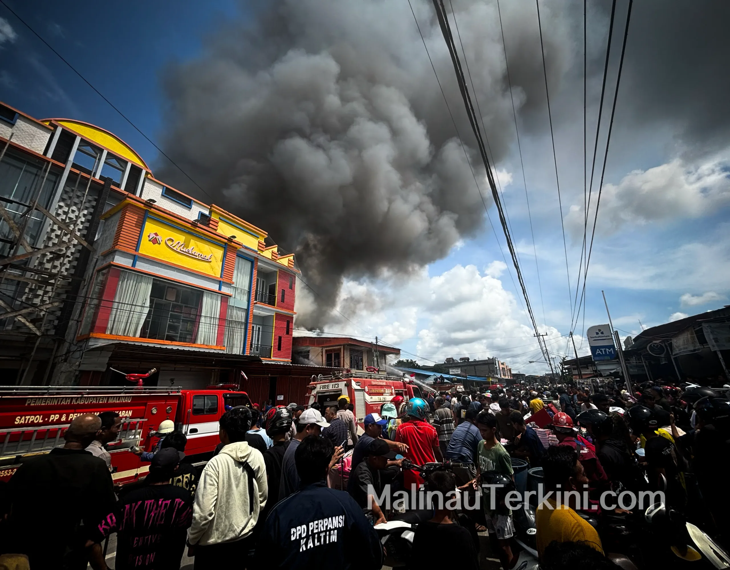 Mobil damkar memadamkan kebakaran besar di Pasar Pelangi Malinau dengan asap pekat.
