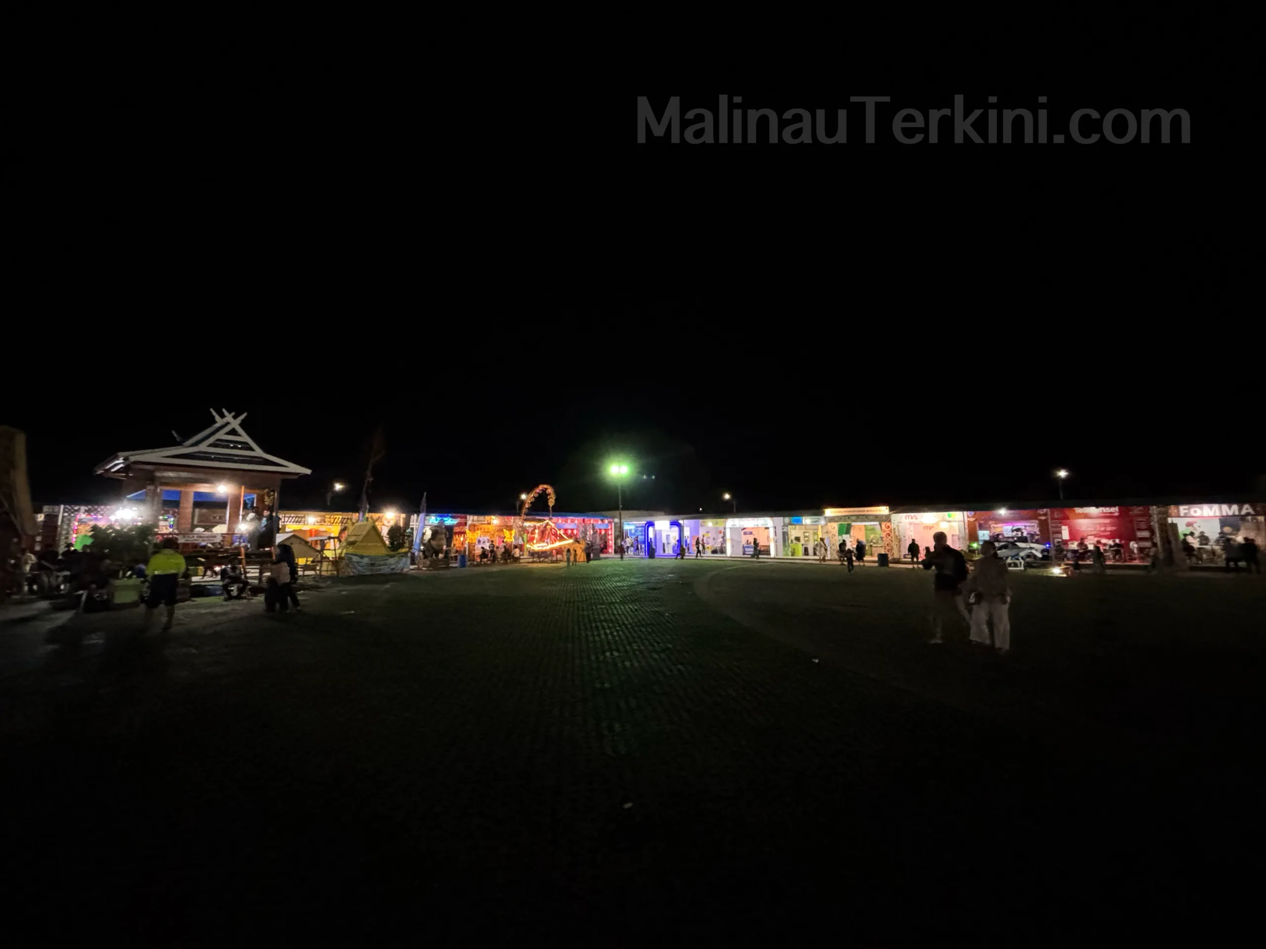 Suasana Malam di Stan Irau Malinau 2025 Suasana malam di stan Irau Malinau tahun 2025 dengan keramaian pengunjung dan dekorasi lampu warna-warni.