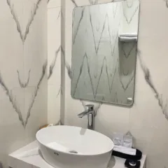 Wastafel modern Hotel Dotaga Malinau dengan perlengkapan mandi lengkap dan desain interior marmer.