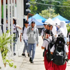 Pelajar SD dan SMA berjalan pulang sekolah di kawasan Malinau dengan latar kegiatan masyarakat. Foto menunjukkan aktivitas pendidikan yang menjadi sasaran utama alokasi DAK Nonfisik 2026.