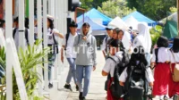 Pendidikan Malinau Pelajar SD dan SMA berjalan pulang sekolah di kawasan Malinau dengan latar kegiatan masyarakat. Foto menunjukkan aktivitas pendidikan yang menjadi sasaran utama alokasi DAK Nonfisik 2026.