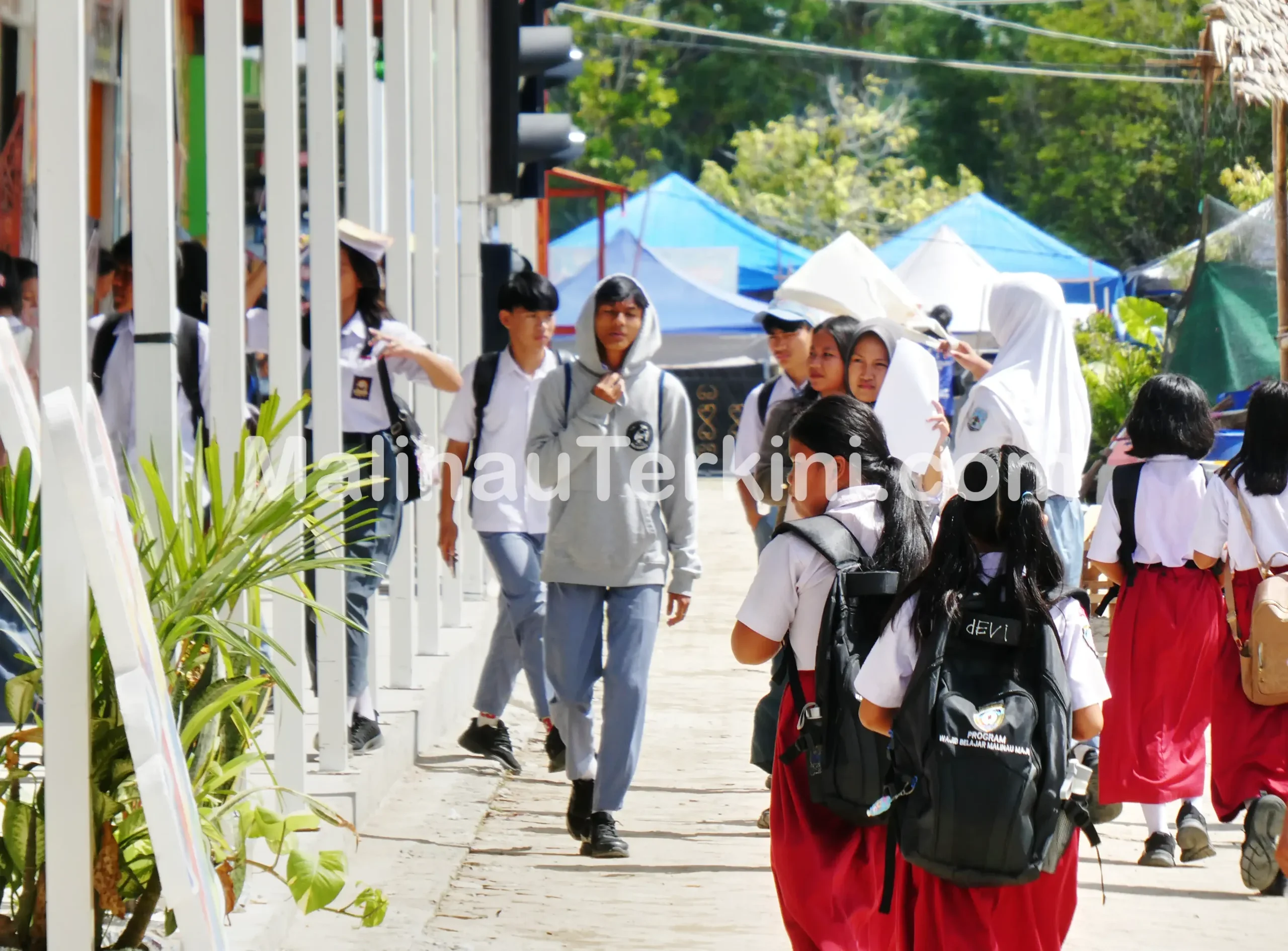 Pelajar SD dan SMA berjalan pulang sekolah di kawasan Malinau dengan latar kegiatan masyarakat. Foto menunjukkan aktivitas pendidikan yang menjadi sasaran utama alokasi DAK Nonfisik 2026.