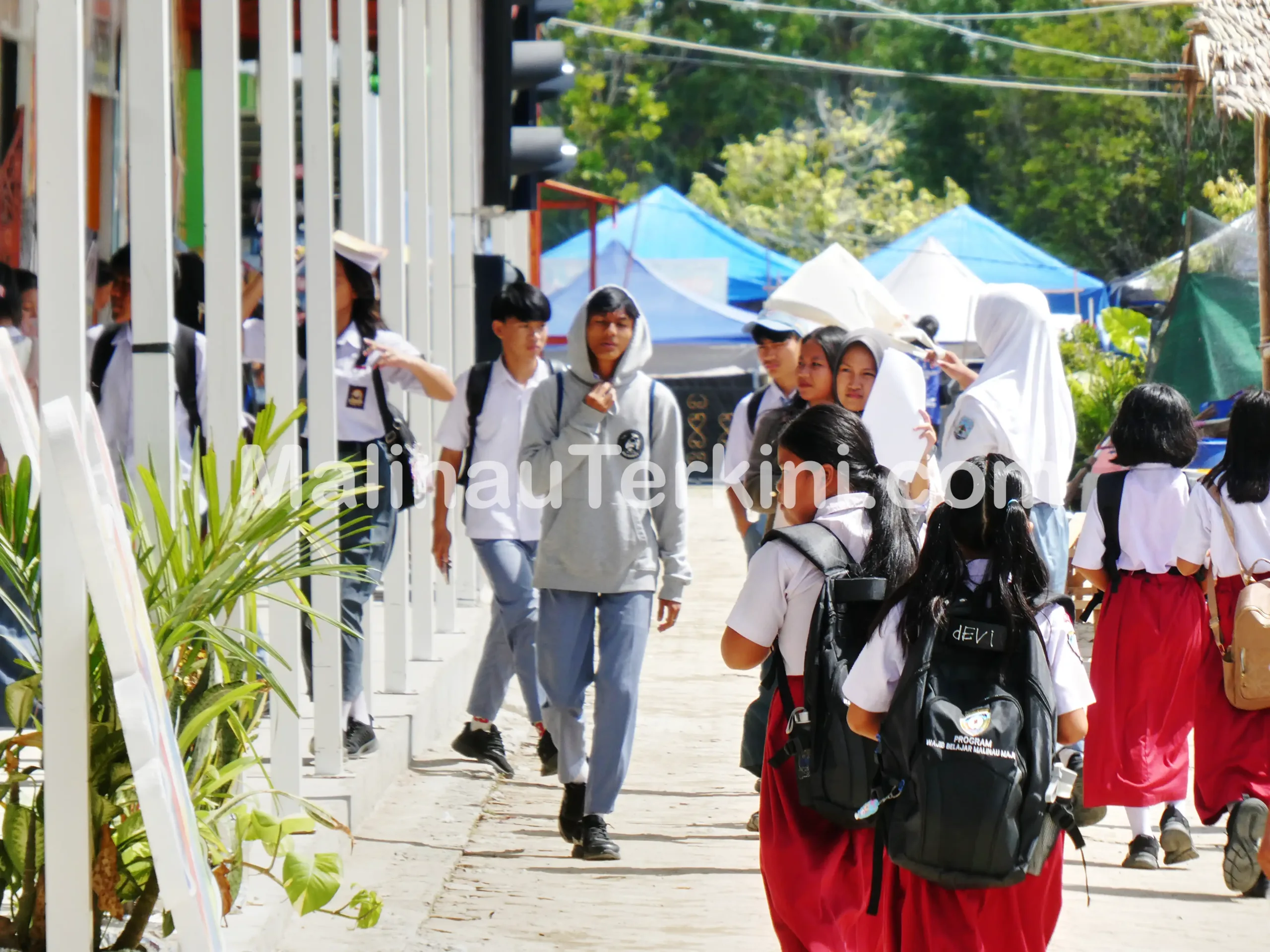 Pelajar SD dan SMA berjalan pulang sekolah di kawasan Malinau dengan latar kegiatan masyarakat. Foto menunjukkan aktivitas pendidikan yang menjadi sasaran utama alokasi DAK Nonfisik 2026.