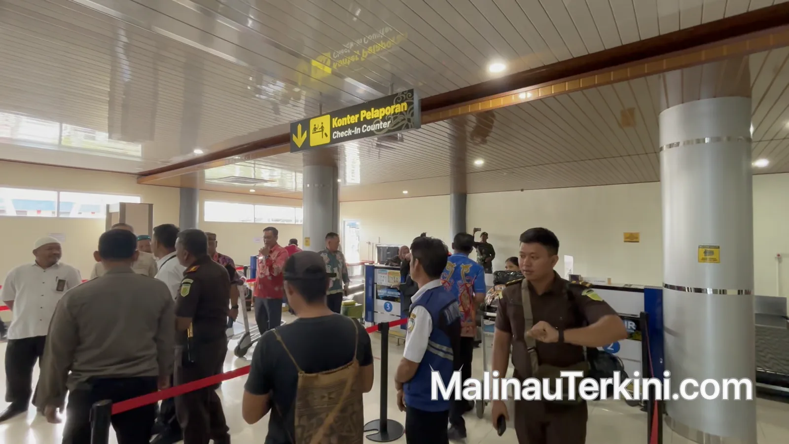 Situasi ruang tunggu keberangkatan Bandara Malinau yang cukup padat oleh penumpang di bawah papan informasi jadwal penerbangan.