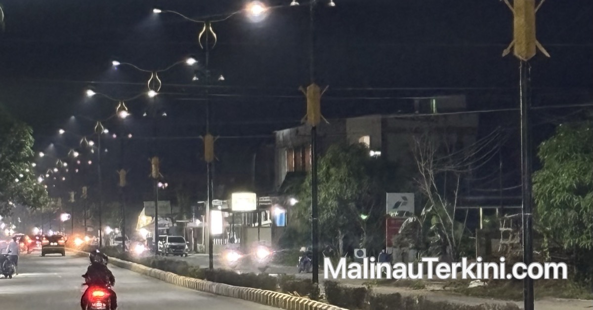 Pemandangan malam hari jalan raya di Malinau yang diterangi lampu jalan dekoratif yang cerah, memperlihatkan kendaraan bermotor melintas di bawah cahaya lampu.